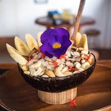 smoothies in the coconut bowl with nuts and edible flower
